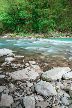 The mountain river Khosta with boulders, stones and pebbles on its sides in springtime. Clear green water of the burly creek in yew-boxwood grove park in Sochi, Adler district, Russia. © EZ2LA
