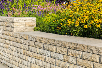 Decorative sandstone wall in the garden and yellow flowers.