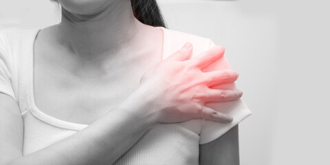 Naklejka premium Asian woman using hand touch her shoulder with feeling stress and pain in inflaming caused by a physical injure and exercise and work out.