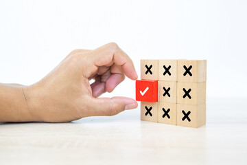 Hand picked check mark on cube wooden toy block stacked with cross symbol for true or false changing mindset or way of adapting to change leader and transform quiz answer and poll concept.