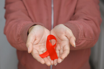 The red ribbon on woman's hand, a symbol of awareness and support for people living with HIV AIDS