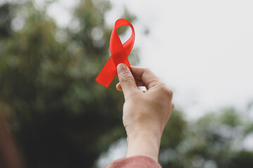 Closeup of a hand holding red awareness ribbon for World AIDS Day.
