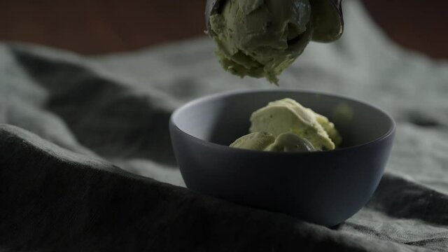Slow motion put a ball of pistachio ice cream into small blue bowl