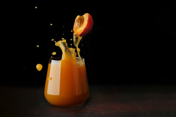 peach or apricot juice pouring in glass. half of fruit levitation. splash of juice into glass. juice concept on dark background