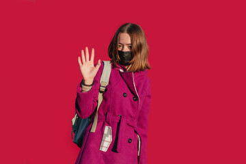 A young girl in a warm coat wearing a protective medical mask