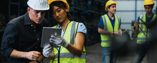 Industrial engineer and businessman in safety helmet working in factory, planning, discussing and training workers with tablet in metalwork place , teamwork and team concept
