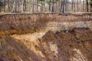 Sharp steep cliff on a sandy quarry, layers of soil, sand and loam