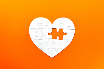 Puzzle pieces on orange background. White heart puzzle pieces grid. Healthcare concept. Copy space...