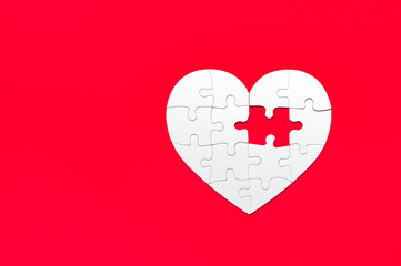 Puzzle pieces on red background. White heart puzzle pieces grid. Healthcare concept. Copy space for...