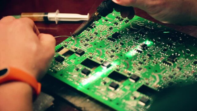 Microcircuits technology. Male hands close-up solder the board. Chip, processor, electrode
