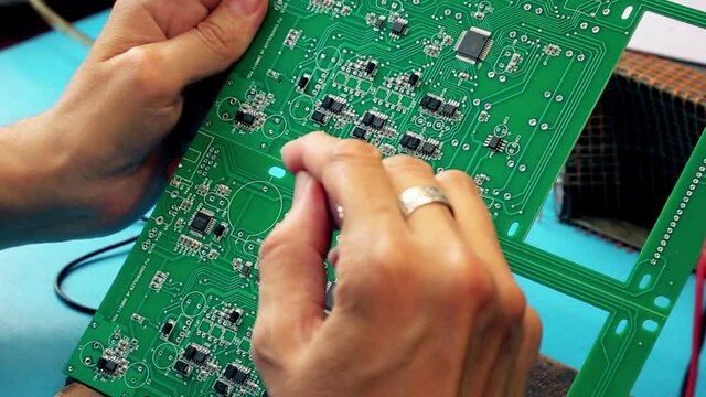 Microcircuits technology. Male hands close-up solder the board. Chip, processor, electrode