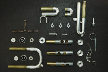 top view of Disassembled trumpet parts on a dark colored table