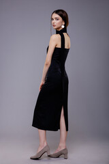 Fashion model in black dress, beautiful young woman. Studio shot. Gray background. 
