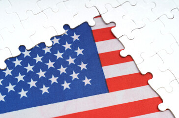 There are white puzzles on a table above the US flag.