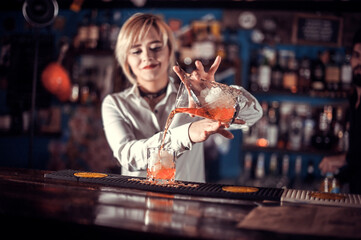 Pretty girl barman demonstrates his skills over the counter at the bar counter