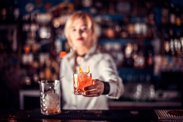 Girl barman makes a cocktail at the saloon