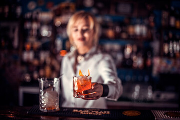 Girl barman formulates a cocktail in the taproom