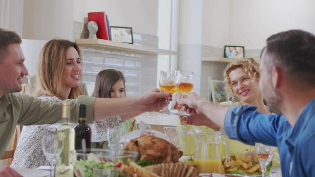 Happy friends having dinner together with each other and clinking glasses at home indoor. Relationships and holidays concept