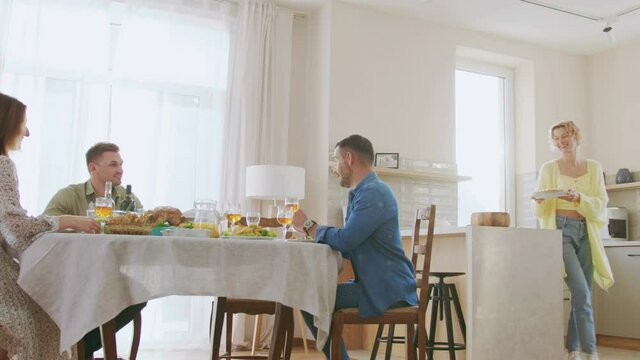 Group of multi generation people having fun, Communicating and eating at indoor family dinner. Woman bringing tasty pie. Relationship and parties concept
