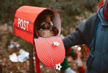 woman holds a red polka dot retro mailbox with Christmas gifts toys as well as a congratulatory...
