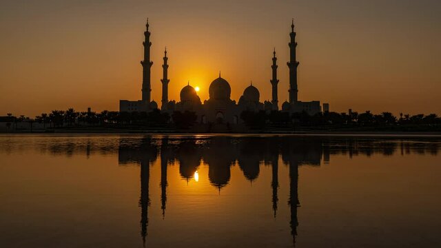 Sheikh Zayed Grand Mosque in Abu Dhabi in UAE- Time Lapse of day to night transition seen from Wahat Al Karama with the mosque reflected in pond