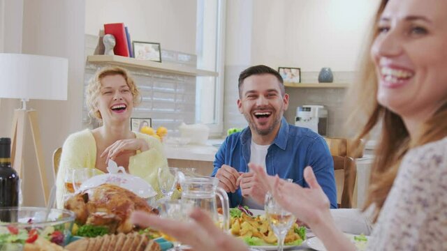 Waist up portrait view of the multi generation family sitting at the dining table during festive dinner, feeling happy, drinking wine and talking