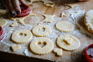 Women's hands making gingerbread christmas cookies with metal cutter