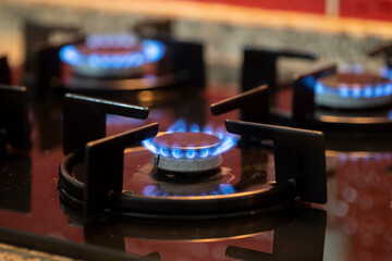 The gas burns in the burner of a kitchen stove. Horizontal view