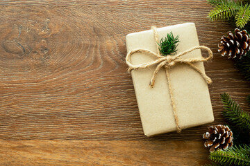 Beautiful Christmas background with gift box, decorate with pine branch and pine cone over wood background. Top view with copy space, flay lay.