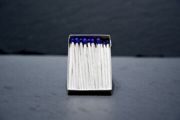  matchbox and blue match sticks on a grey background