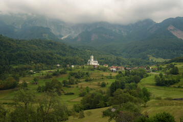 Fototapeta na wymiar Foggy alpine landscape of Dreznica village in a summer stormy day, Slovenia, Europe