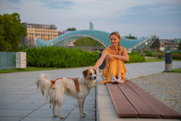 in Rike park a girl sits on a bench with a dog in tbilisi