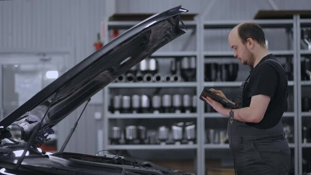 Using Digital Tablet For A Car Diagnostic. mechanic using a tablet pc at the repair garage . Interactive Diagnostics Software on an Advanced Computer.