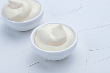 mayonnaise, homemade mayonnaise in a saucepan on a white background, concrete background