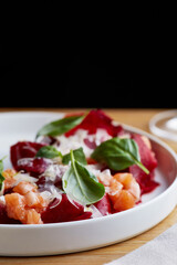 salmon salad with beet cheese and green leaves on wooden table closeup.