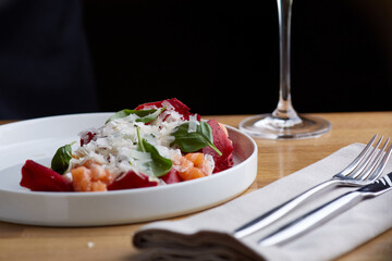 salmon salad with beet cheese and green leaves on wooden table with glass of white wine.