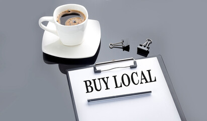 BUY LOCAL text on the paper sheet with coffee on the black background
