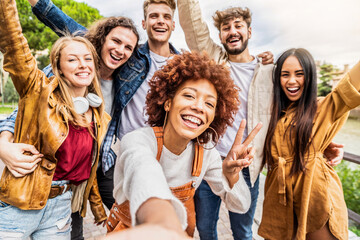 Multicultural best friends having fun taking group selfie portrait outside - Smiling guys and girls...