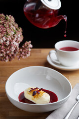 cottage cheese pancakes with berry sauce and red tea. breakfast morning table with flowers.