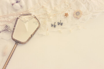 Background of white delicate lace fabric, pearls and vintage hand mirror