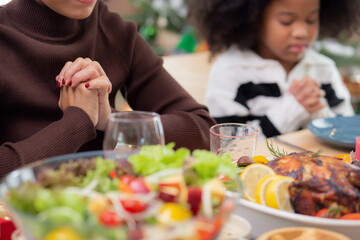 Happy African family holding hands and praying dinner on thanksgiving eve day together, merry Christmas, celebration and festive on food table, relationship of family, indoor, new year and xmas.