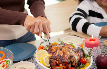 Closeup hands of mother using knife slicing meat of turkey roasted on dishes for eating at home on thanksgiving eve day, celebration of xmas with dining with family, new year, festive and holiday.