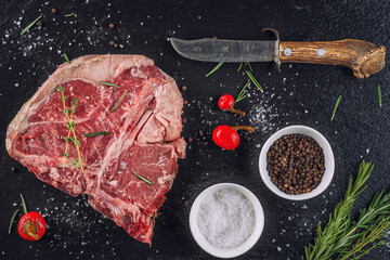 Raw beef steak fillet with ingredients like sea salt, pepper, onion and herbs on black board, product image for restaurant