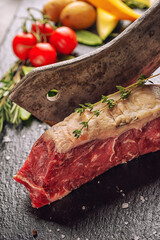 Raw beef steak fillet with ingredients like sea salt, pepper, onion and herbs on black board, product image for restaurant