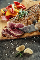 Grilled beef steak fillet with ingredients and herbs on black board, product image for restaurant