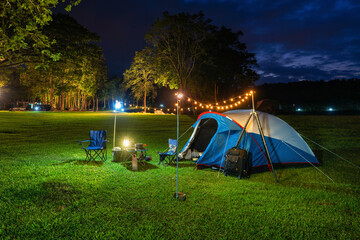 Camping tent and outdoor kitchen equipment at night in the park.