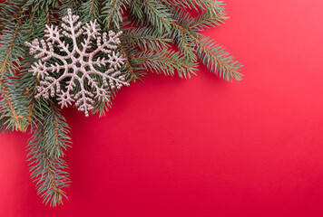 Christmas fir branches and decorative snowflake on a red background.