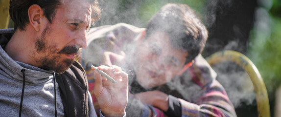 Two young friends smoking cannabis marijuana ganja or hashish joint