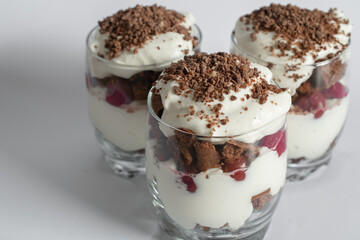 Biscuit cake with cream and cherries in a glass on a white background