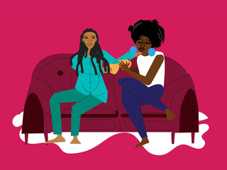 Lesbian couple sharing a cup of cocoa on the couch
